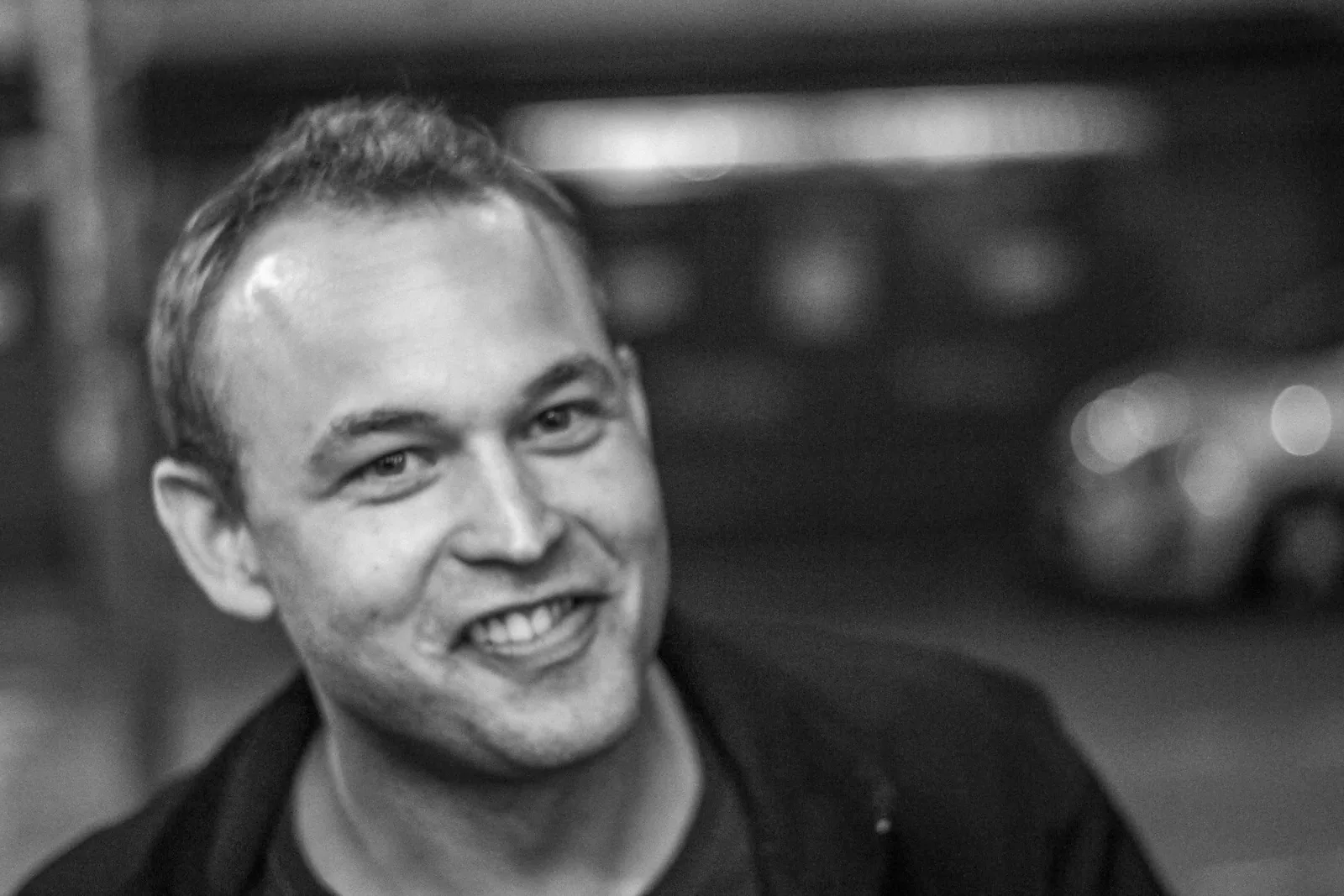 A man smiling toward the camera in a black-and-white Copenhagen portrait.